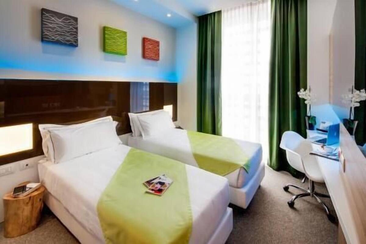 A hotel room with two beds, a desk, and a chair.
