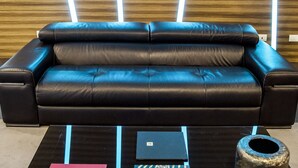 A modern sofa with a black and blue color scheme, a glass coffee table with books and a small sculpture, and a wooden wall with vertical light strips. - Hotel Degli Arcimboldi (Milan)