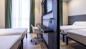 Habitación de hotel con dos camas, un escritorio con silla, televisor montado en la pared y ventana con cortinas.
