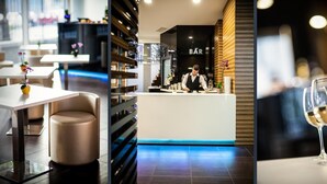 Zona de bar moderna con un barman, una barra blanca y una copa de vino.