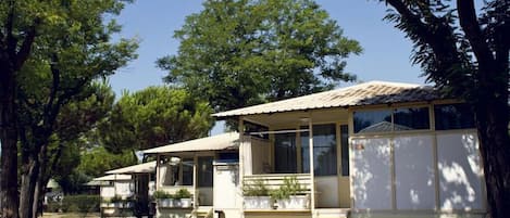 A row of mobile homes with attached porches, surrounded by trees.