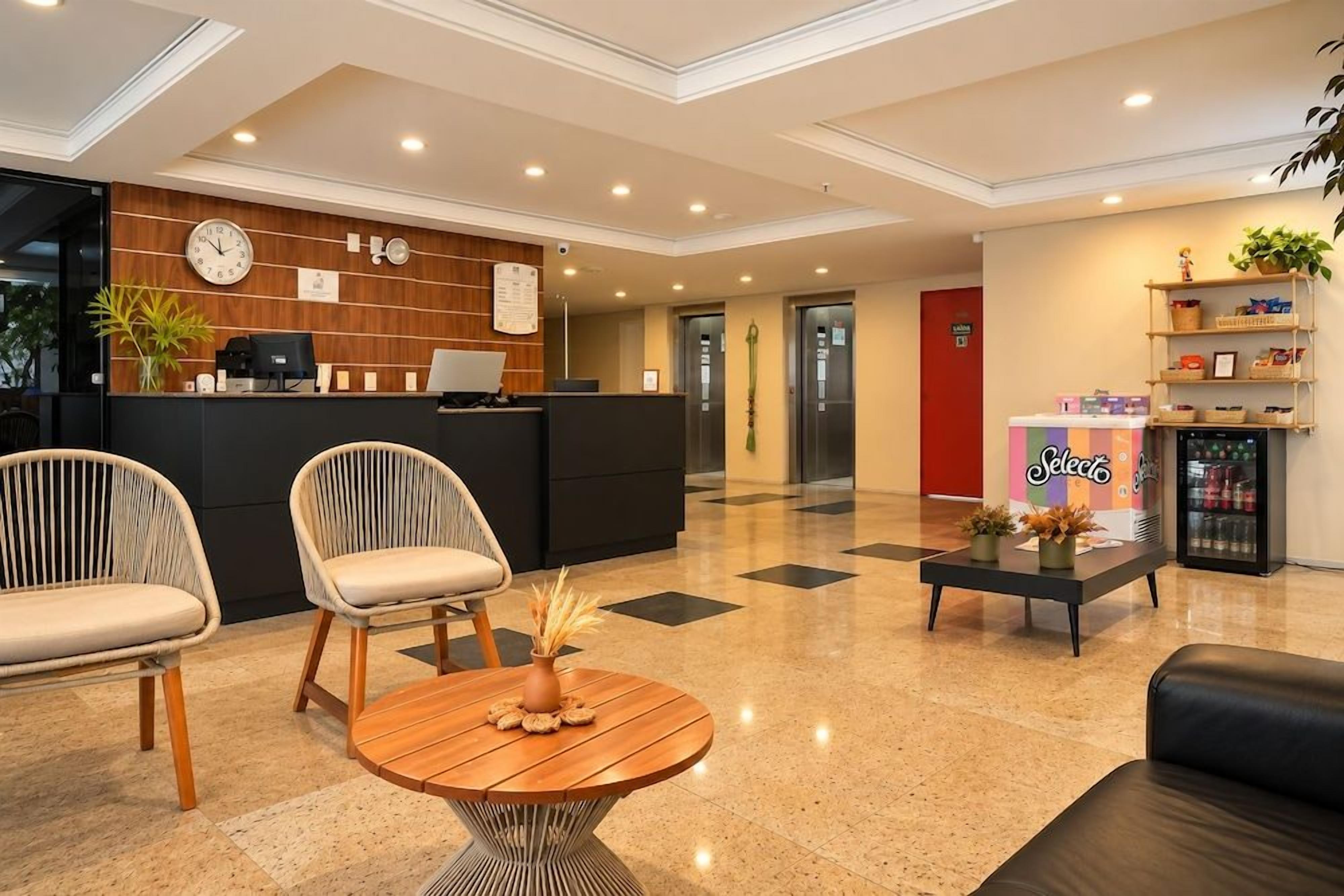 Um hall de hotel com balcão de recepção, área de estar e máquina de café.