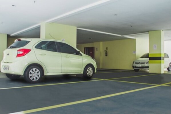 Un garaje de estacionamiento con un automóvil blanco aparcado en un espacio reservado.