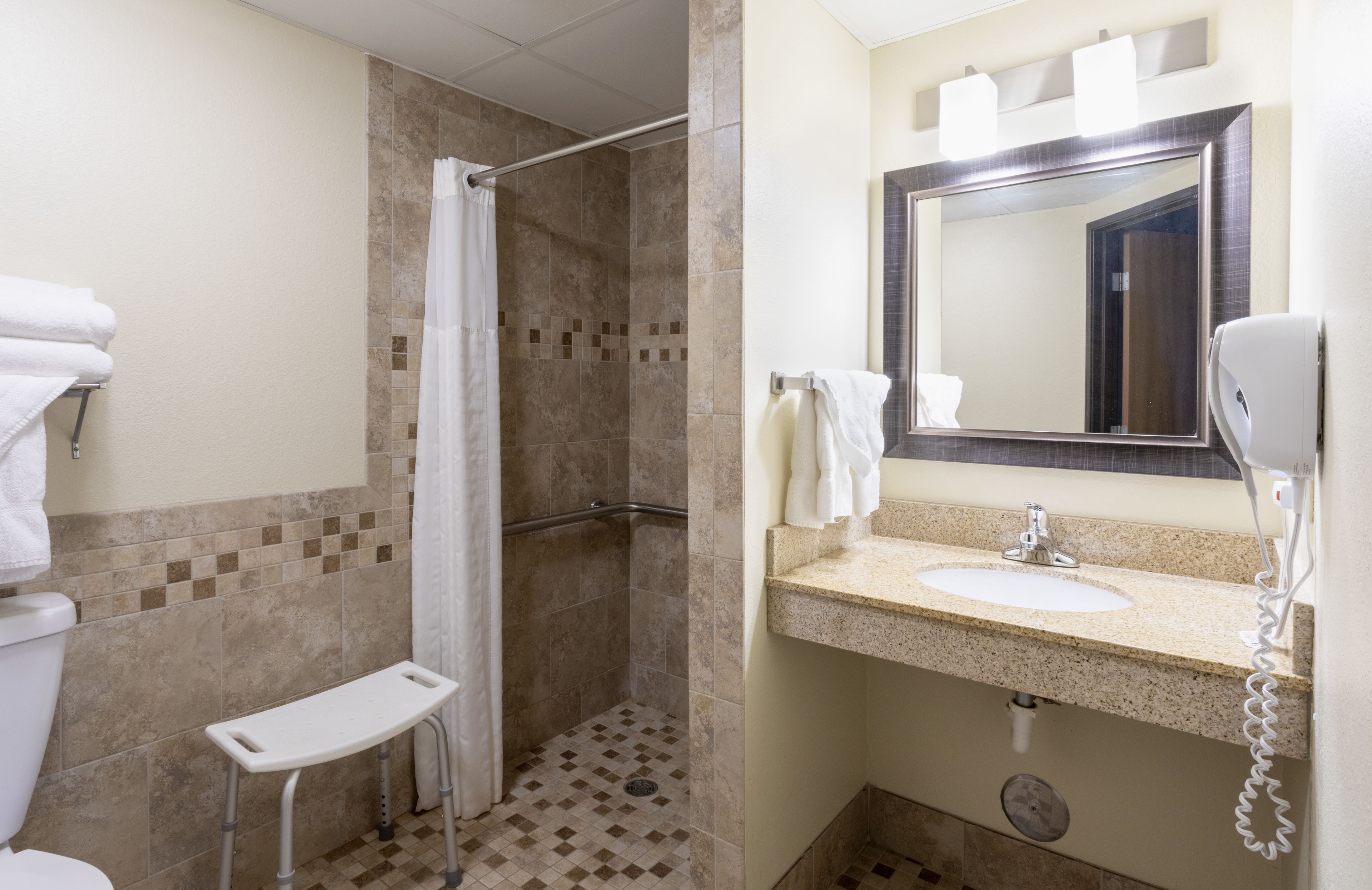 Un baño con ducha, lavabo, espejo e inodoro.