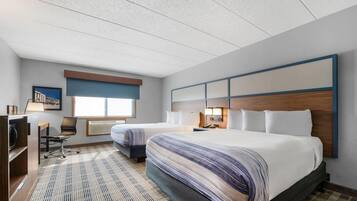 A hotel room with two beds, a desk, and a chair.