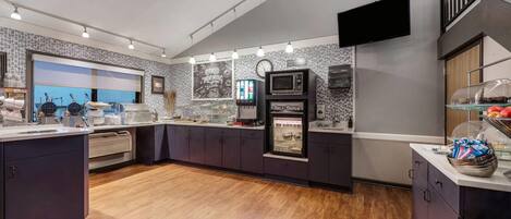 A modern kitchen with a self-serve station, a microwave, and a clock on the wall.