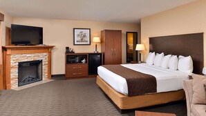 A hotel room with a large bed, a fireplace, a television, a desk, and a wardrobe. - AmericInn by Wyndham Fergus Falls - Conference Center (Fergus Falls)
