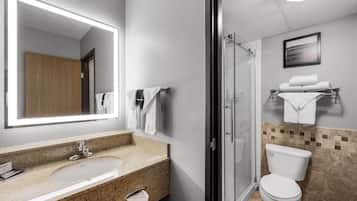 A bathroom with a sink, mirror, towel rack, toilet, and shower.