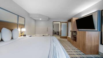 A hotel room with a large bed, a TV, a microwave, and a bathroom visible through an open door.