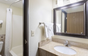 A bathroom with a shower, toilet, sink, and a mirror.