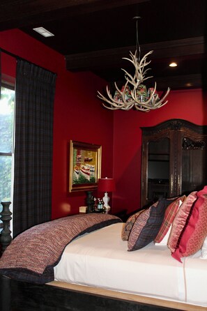 A bedroom with a large bed, a chandelier, a painting, and a mirror. - The Wheeler Mansion (Chicago)