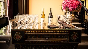 Een tafel met wijnflessen, glazen en een decoratieve vaas met bloemen.