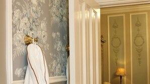 Een badkamer met een witte badkuip, een handdoekrek met handdoeken, een deur en een behangen muur.