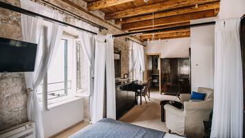 A bedroom with a bed, a desk, and a chair. There is a TV mounted on the wall.