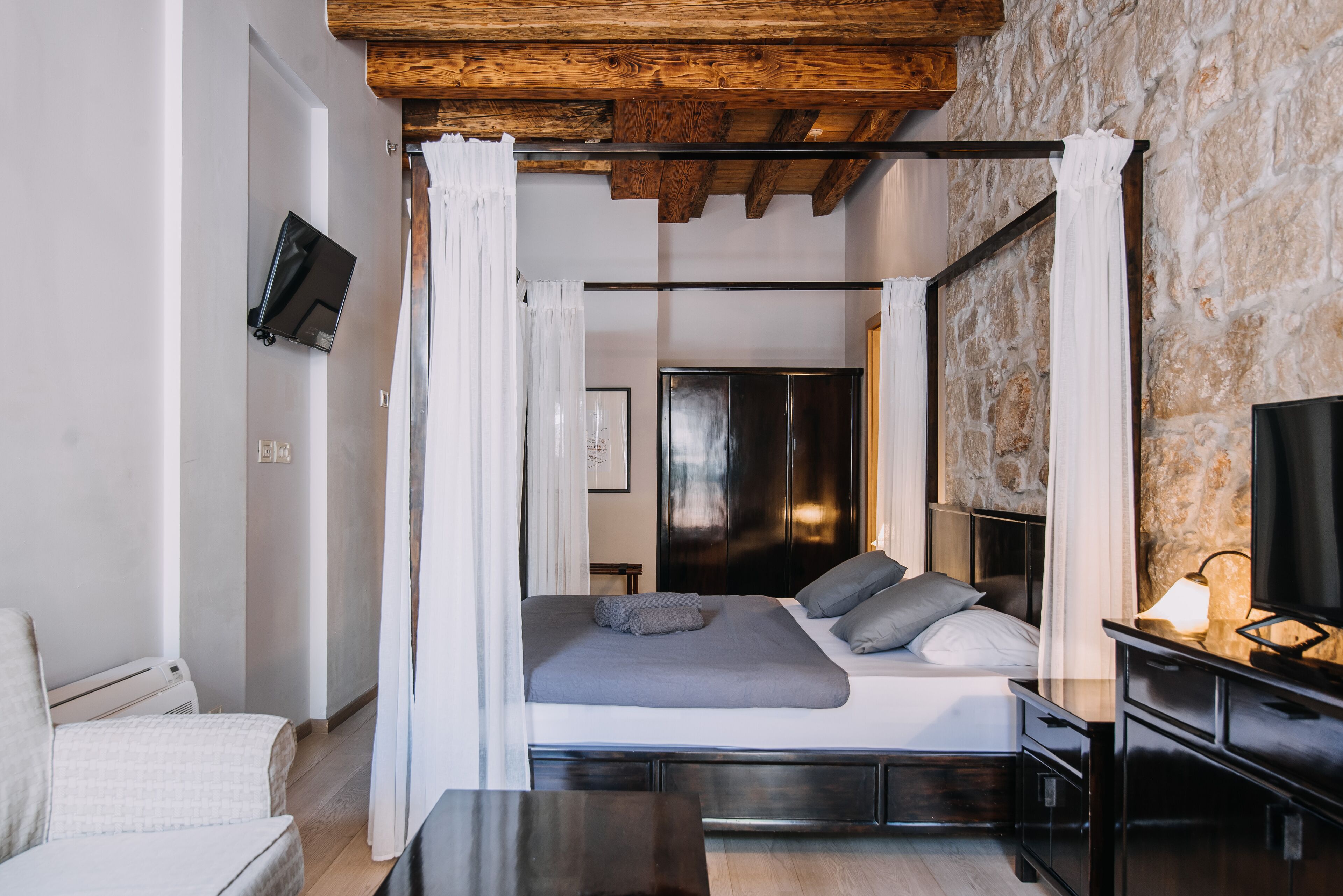 Una camera da letto con un letto, un comodino e una TV montata a parete.