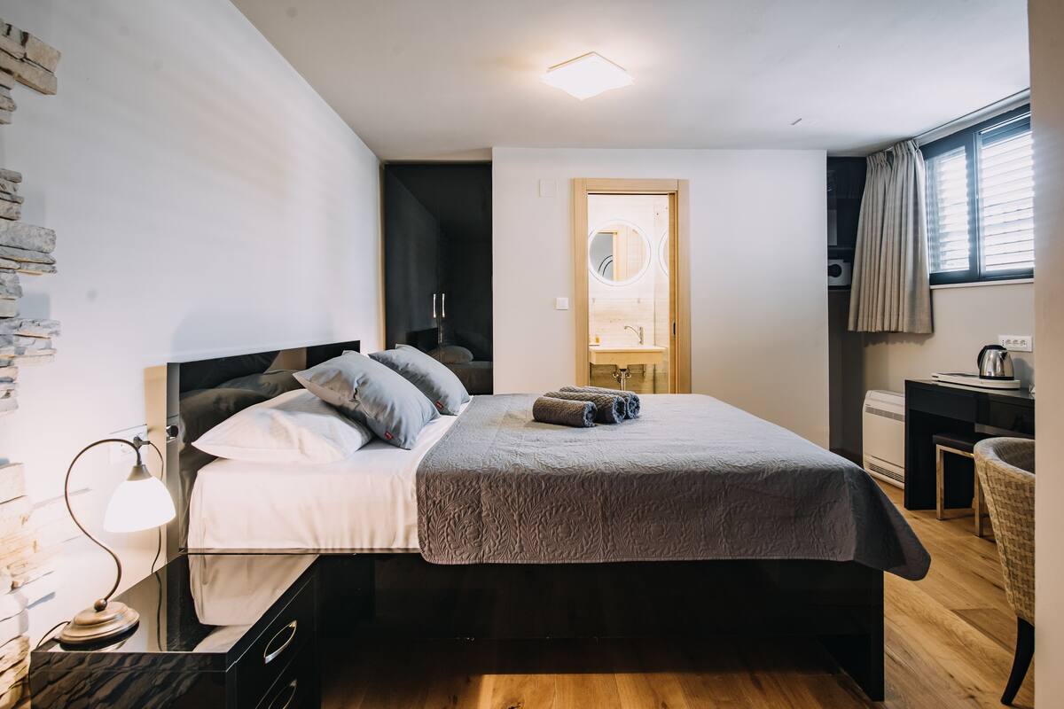 Een moderne slaapkamer met een bed, bedlampje en een klein bureau met stoel.