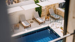 Un área de piscina en la azotea con sillones de descanso y sombrillas.