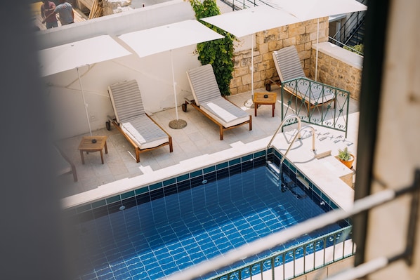 Uma área de piscina no terraço com espreguiçadeiras e guarda-sóis.