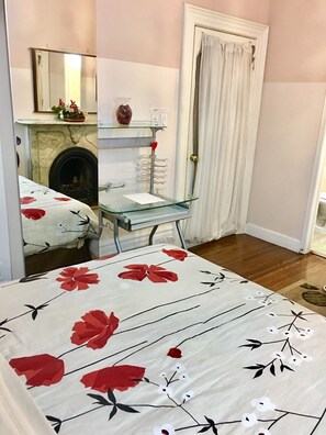 A bedroom with a bed, a glass table, a fireplace, and a door with curtains. - Comfy Guest House (Toronto)