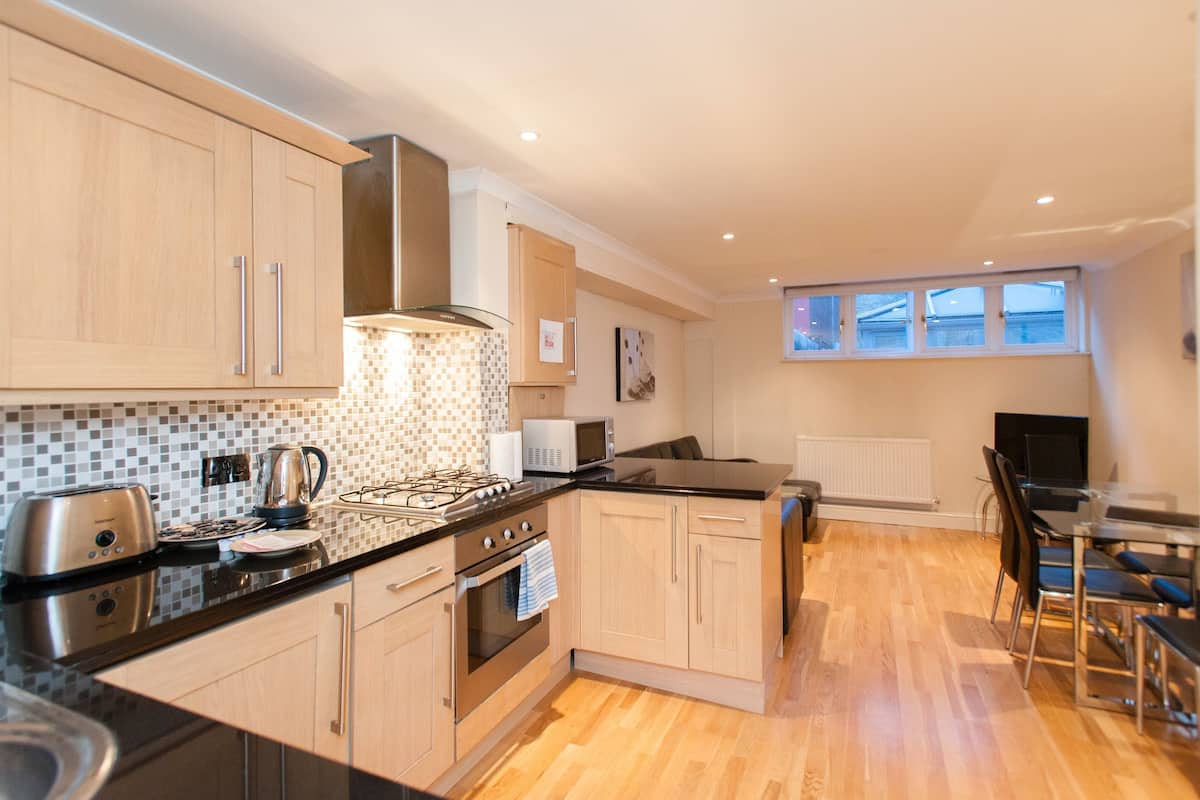 A modern kitchen with wooden cabinets, a black countertop, and a built-in stove.