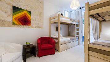 A room with bunk beds, a red chair, a small table, and a colorful wall art piece.
