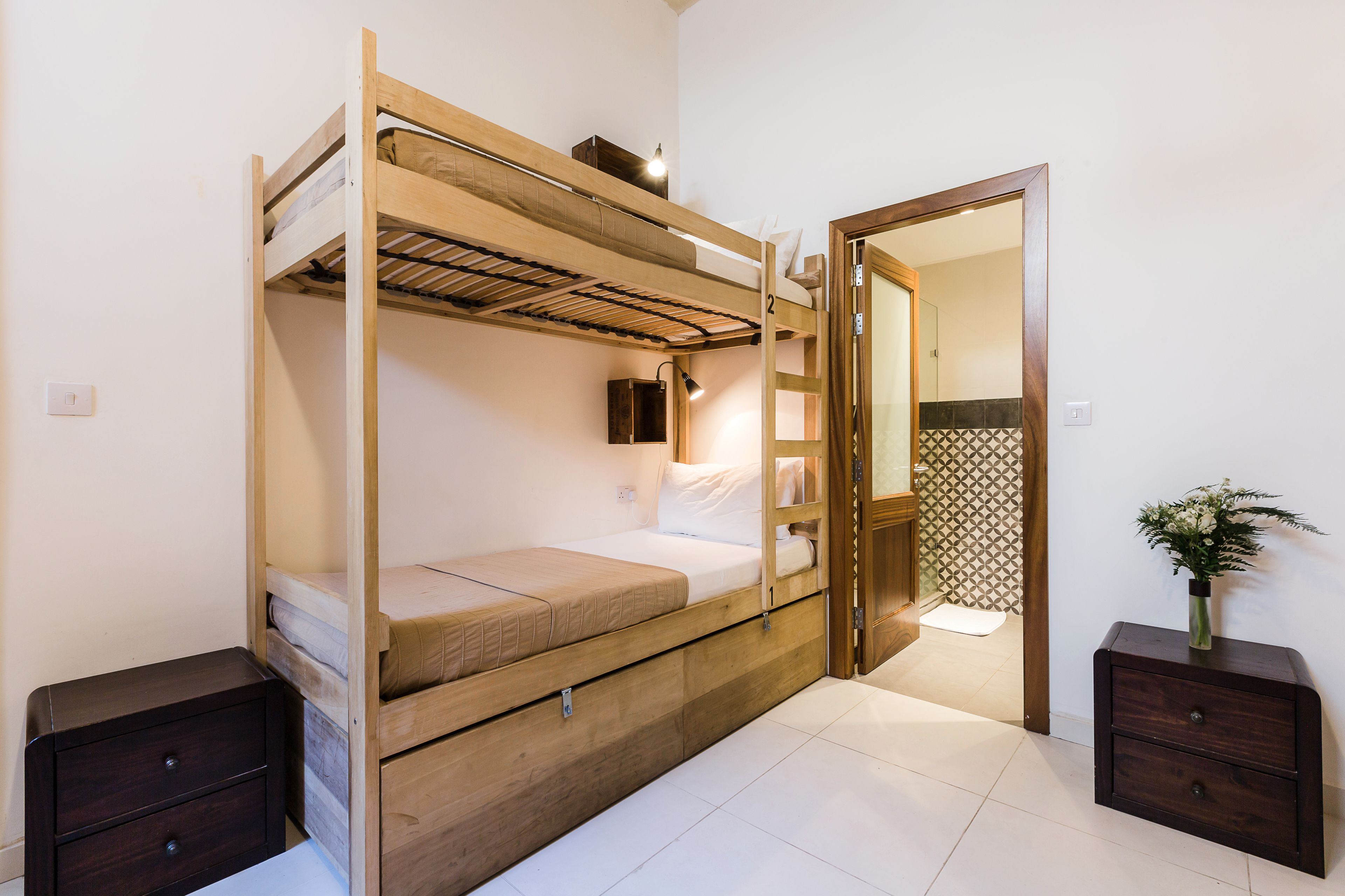A bunk bed room with a small bedside table and a nightstand.