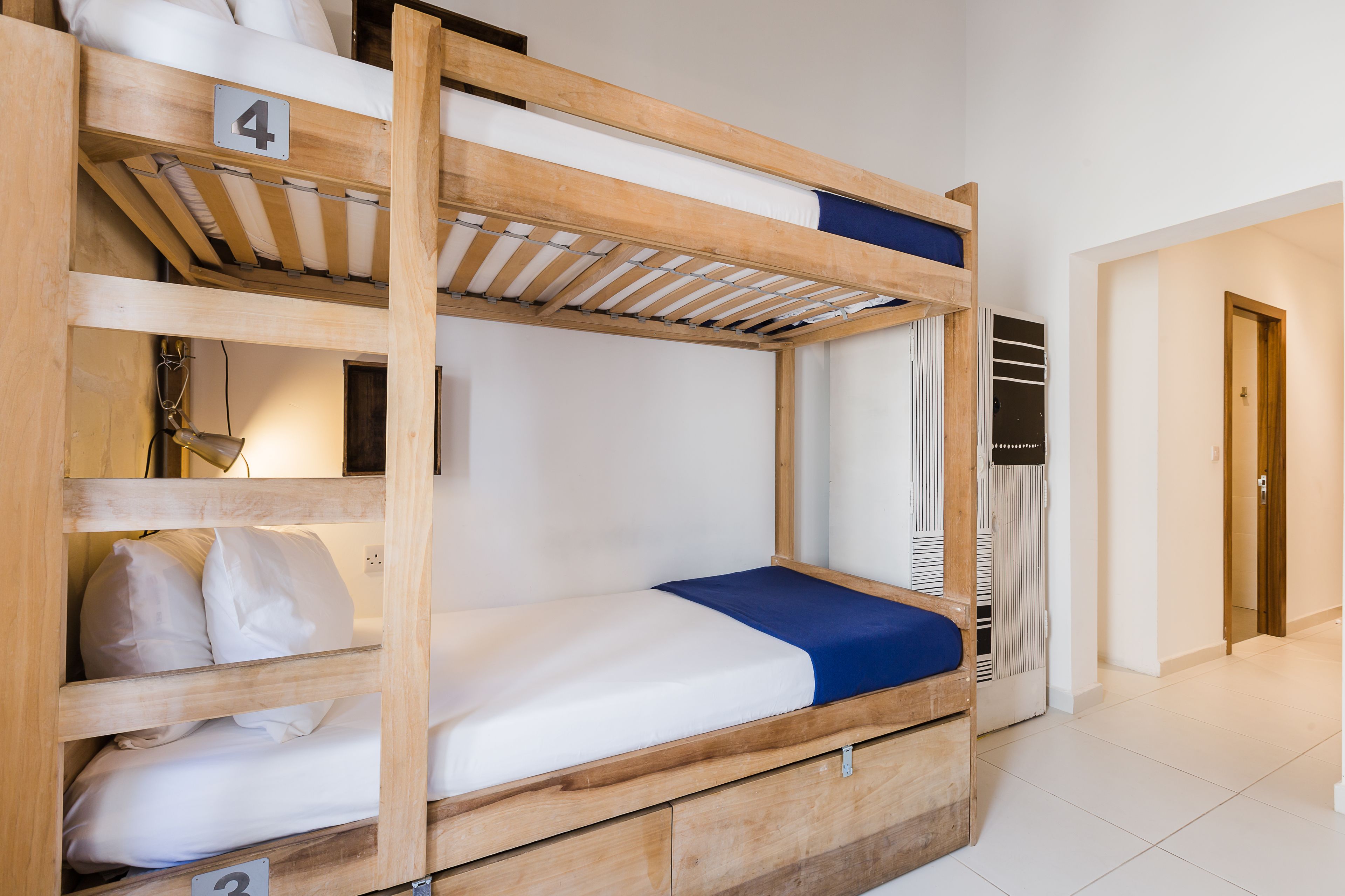 A bunk bed with a wooden frame, a number 4 sign, and a number 3 sign on the lower bunk.