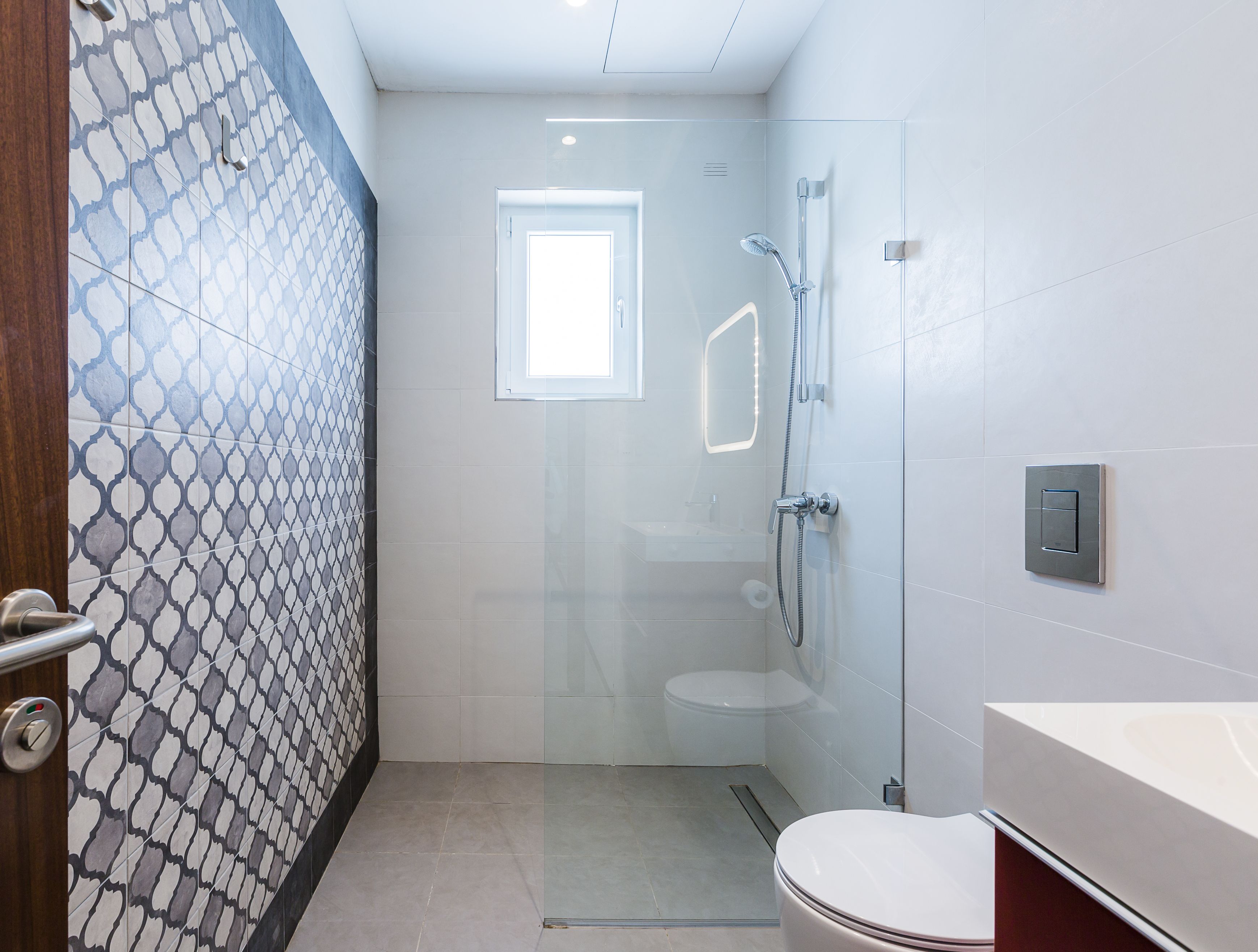 A modern bathroom with a glass shower enclosure, a toilet, and a sink with a mirror.