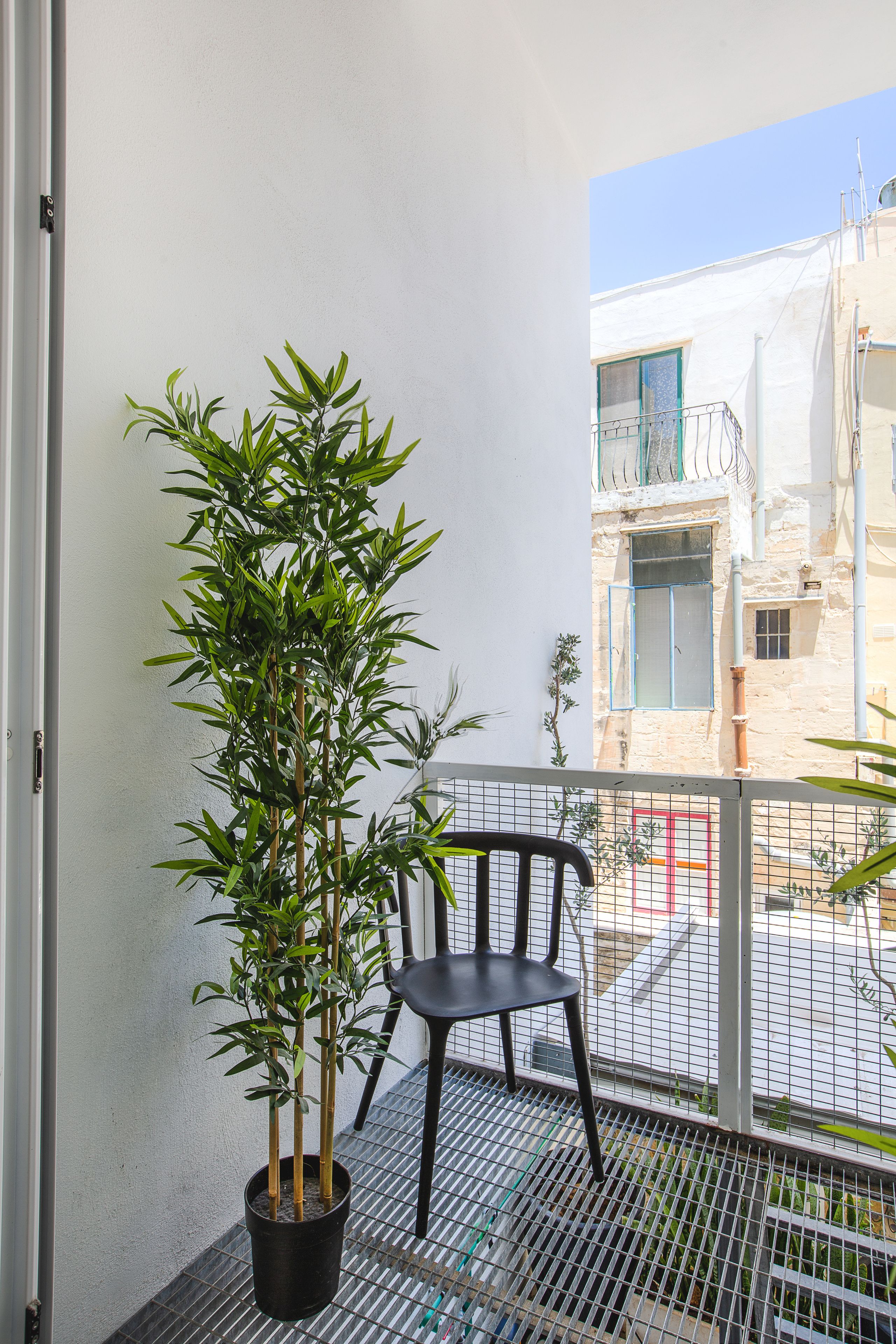 A balcony with a potted plant and a chair.