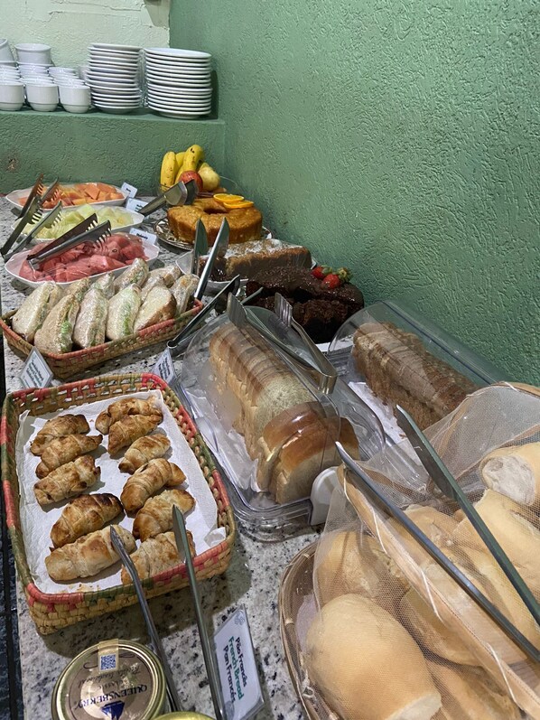 A buffet with various food items including bread, pastries, and fruits.