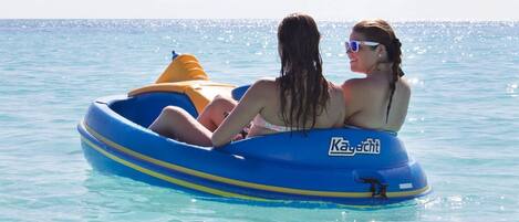 Deux personnes se trouvent dans un radeau gonflable bleu, sur une étendue d’eau calme.