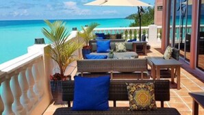 A balcony with outdoor furniture, a view of the ocean, and a large umbrella providing shade. - Pompano Beach Club (Southampton Parish)