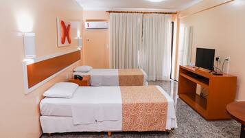 A hotel room with two beds, a TV, a desk, and a mirror.