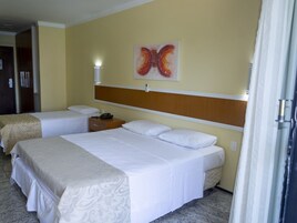 Una habitación de hotel con dos camas, cabecera de madera, una obra de arte en la pared y una mesita de noche con lámpara.