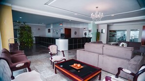Una sala de estar moderna con una mesa de billar, sofás y una cocina al fondo.