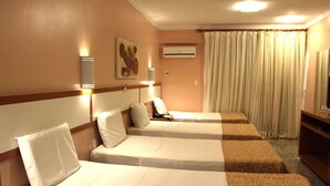 Habitación de hotel con dos camas, una mesita de noche, una lámpara, un equipo de aire acondicionado y una cortina.