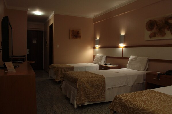 A hotel room with two beds, a desk, and a reception area.