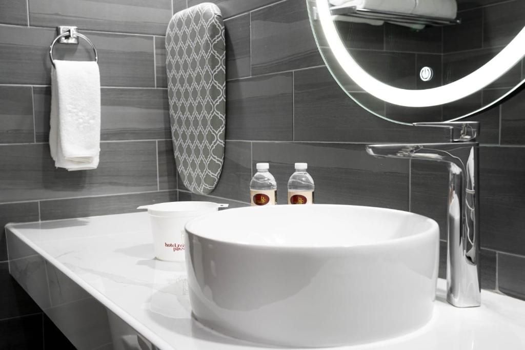 A modern bathroom with a white sink, a towel rack, a patterned towel, and two bottles of shampoo.