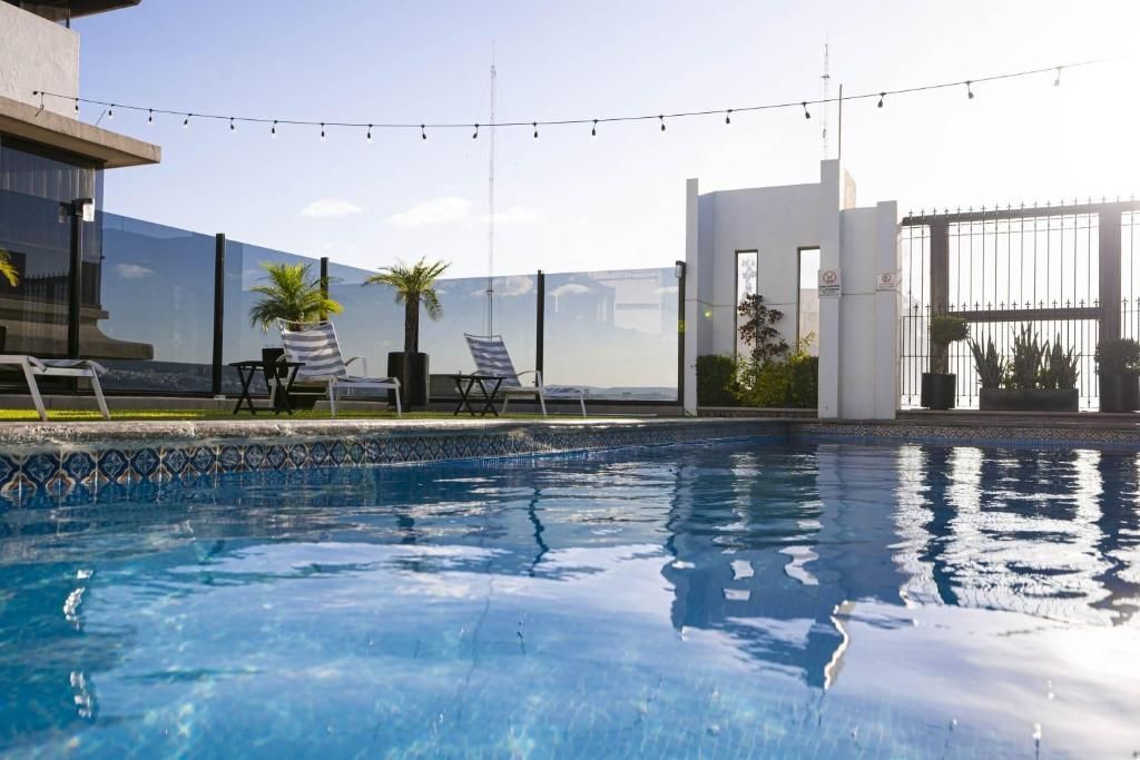 A swimming pool with lounge chairs and a view of the city.