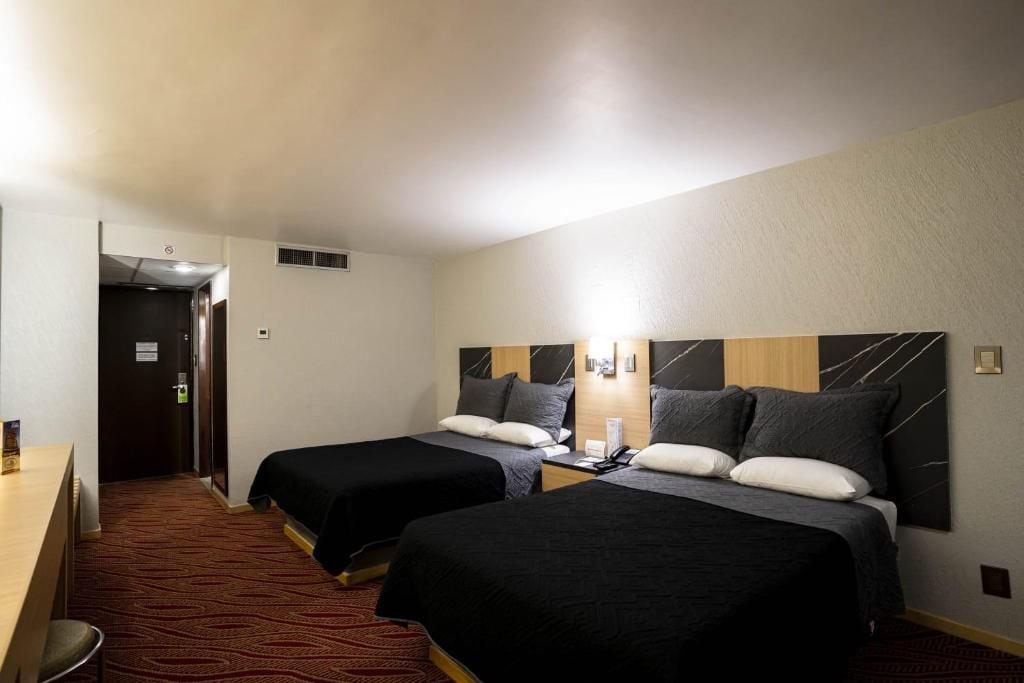 A hotel room with two beds, a desk, and a chair.