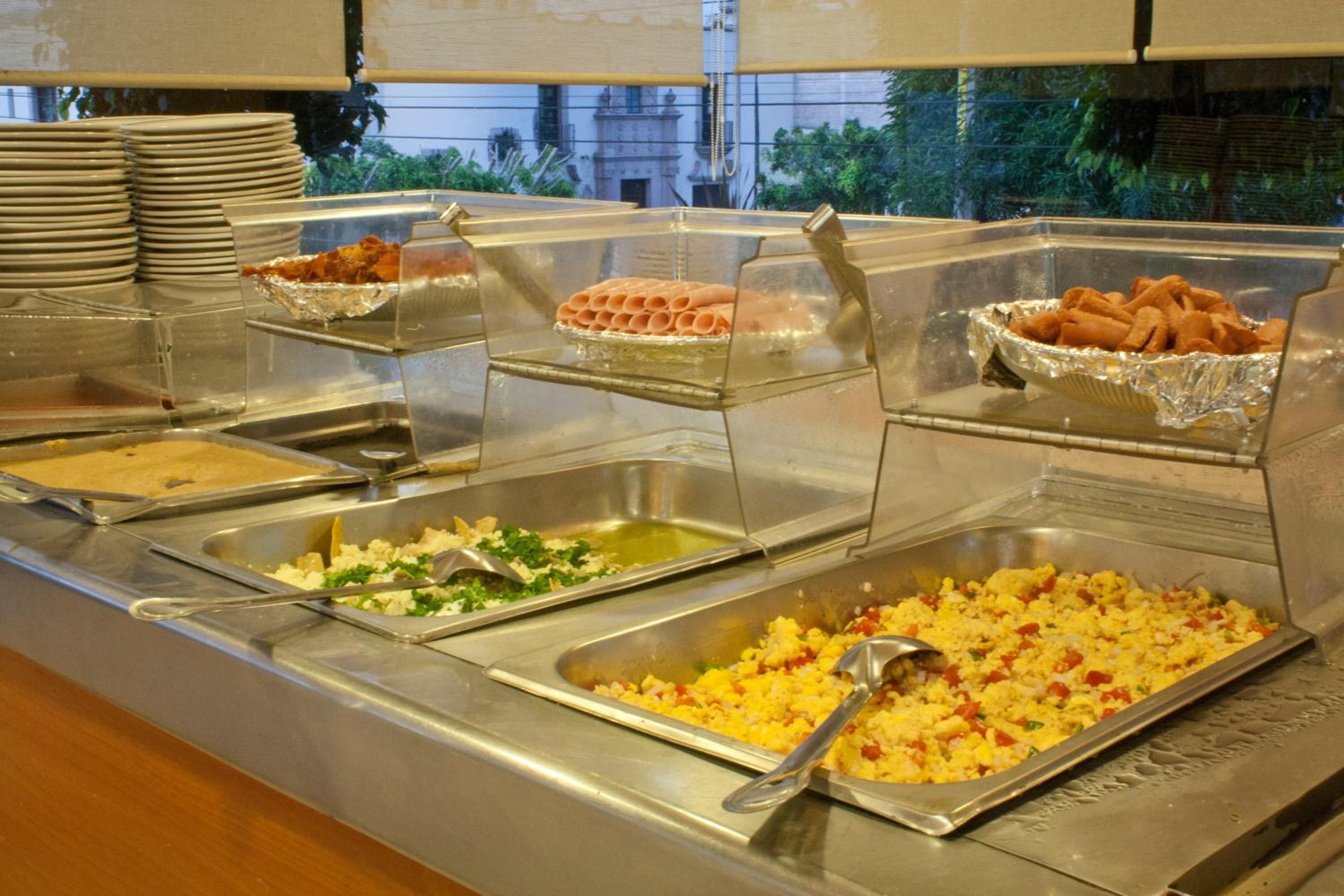 A buffet with various food options, including scrambled eggs, salads, and different types of meat.