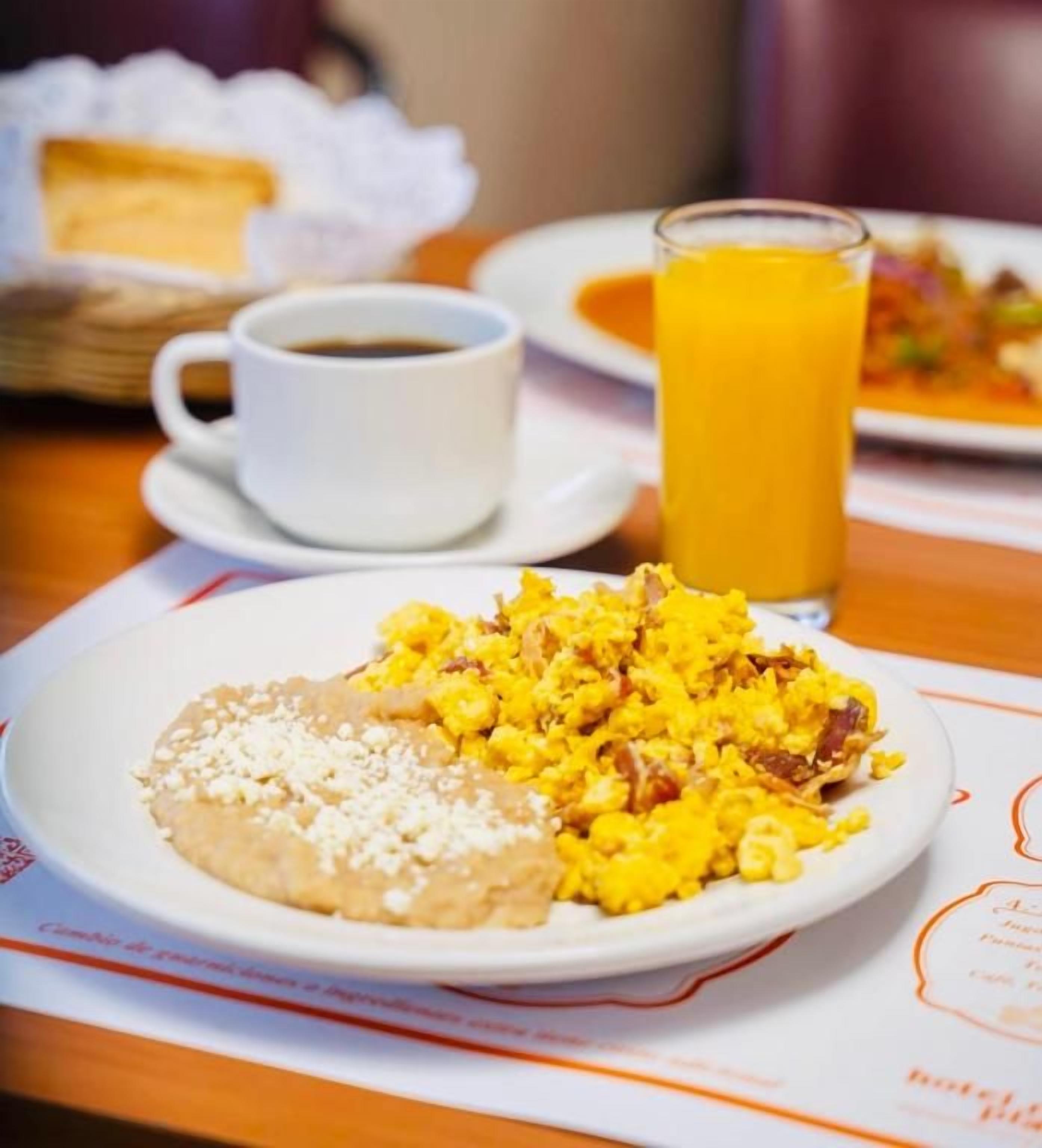 A breakfast setting with a plate of scrambled eggs, a slice of bread, and a glass of orange juice.
