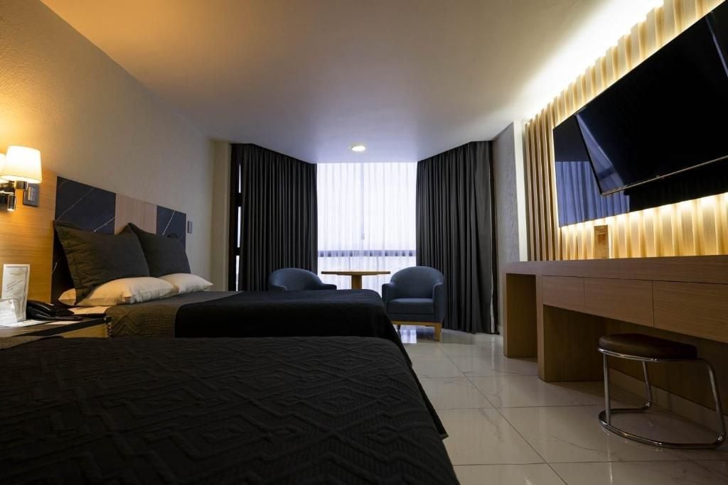 Una habitación de hotel con cama, escritorio, silla y televisor.
