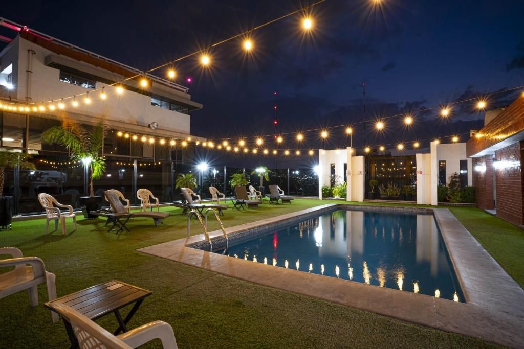 Zona de piscina exterior con sillas de descanso e iluminación con luces.