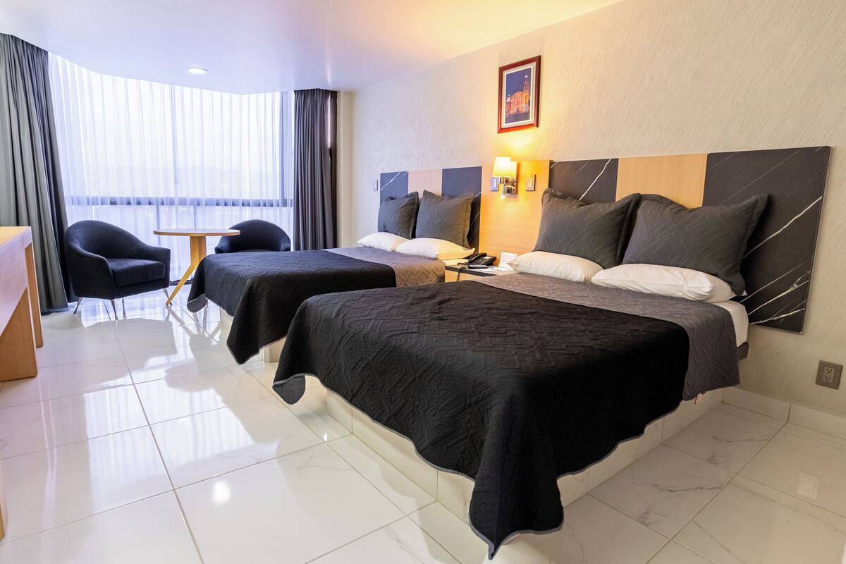 Habitación de hotel con dos camas, un escritorio y una silla.