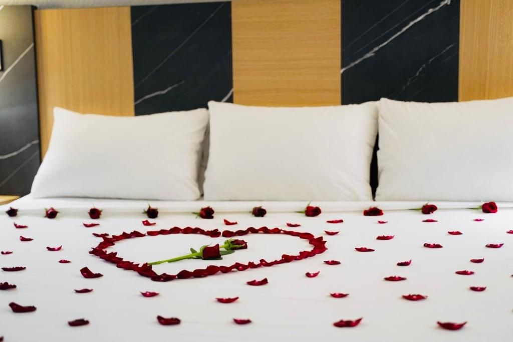 A hotel room with a bed, white bedding, and a rose petal arrangement.