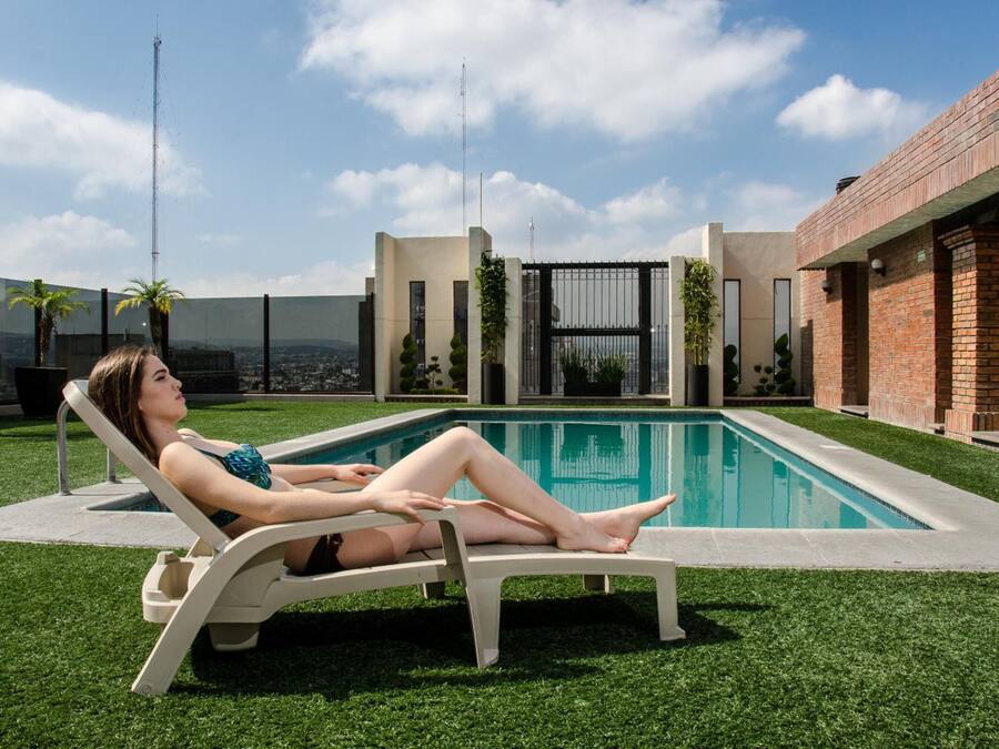 Una donna si rilassa a bordo piscina, con un edificio moderno sullo sfondo.