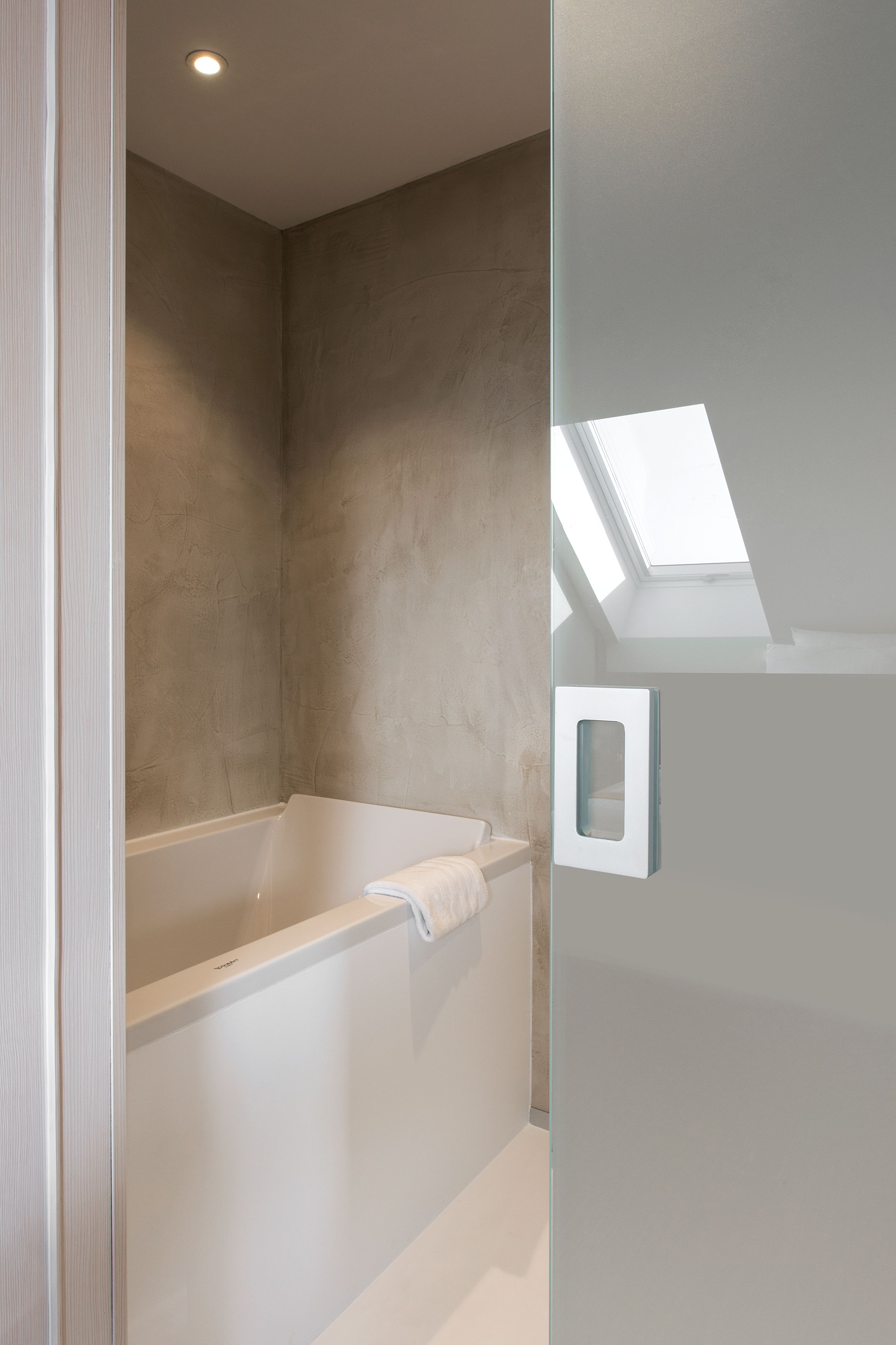 Un baño moderno con una bañera independiente, un tragaluz y una cabina de ducha de vidrio.