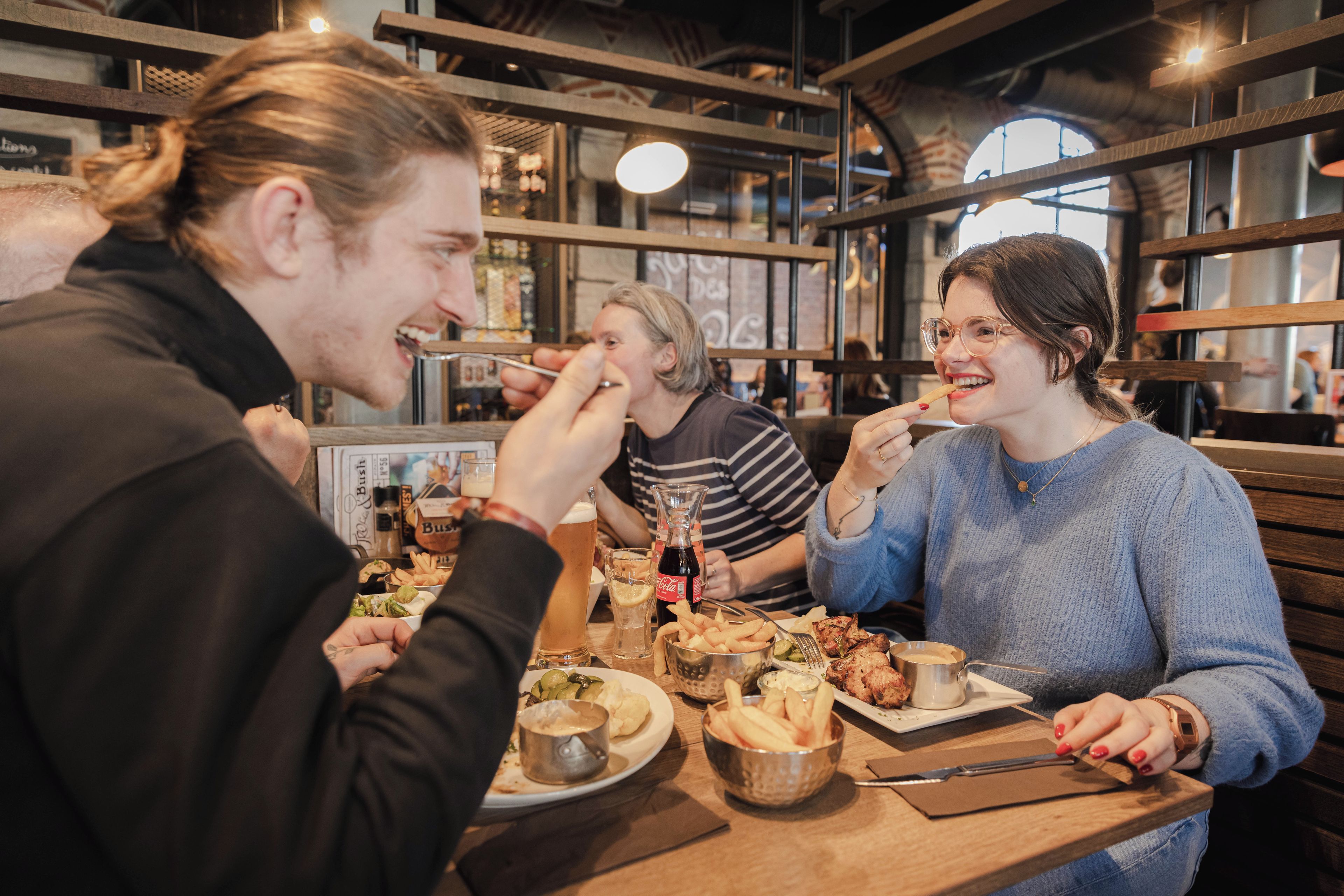 En grupp människor som äter middag på en restaurang med träinredning och synliga tegelväggar.