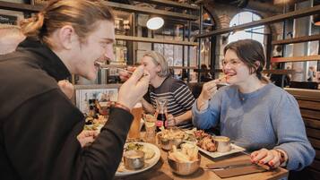 En grupp människor som äter middag på en restaurang med träinredning och synliga tegelväggar.